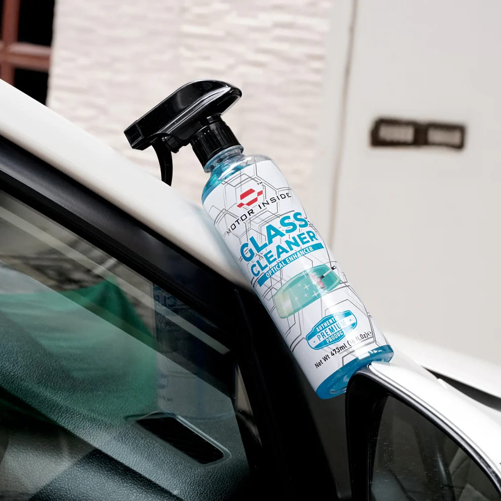 Bottle of glass cleaner being used on a car window