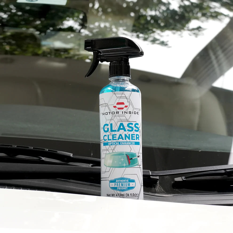 Glass cleaner bottle with a spray nozzle on a car bonet.