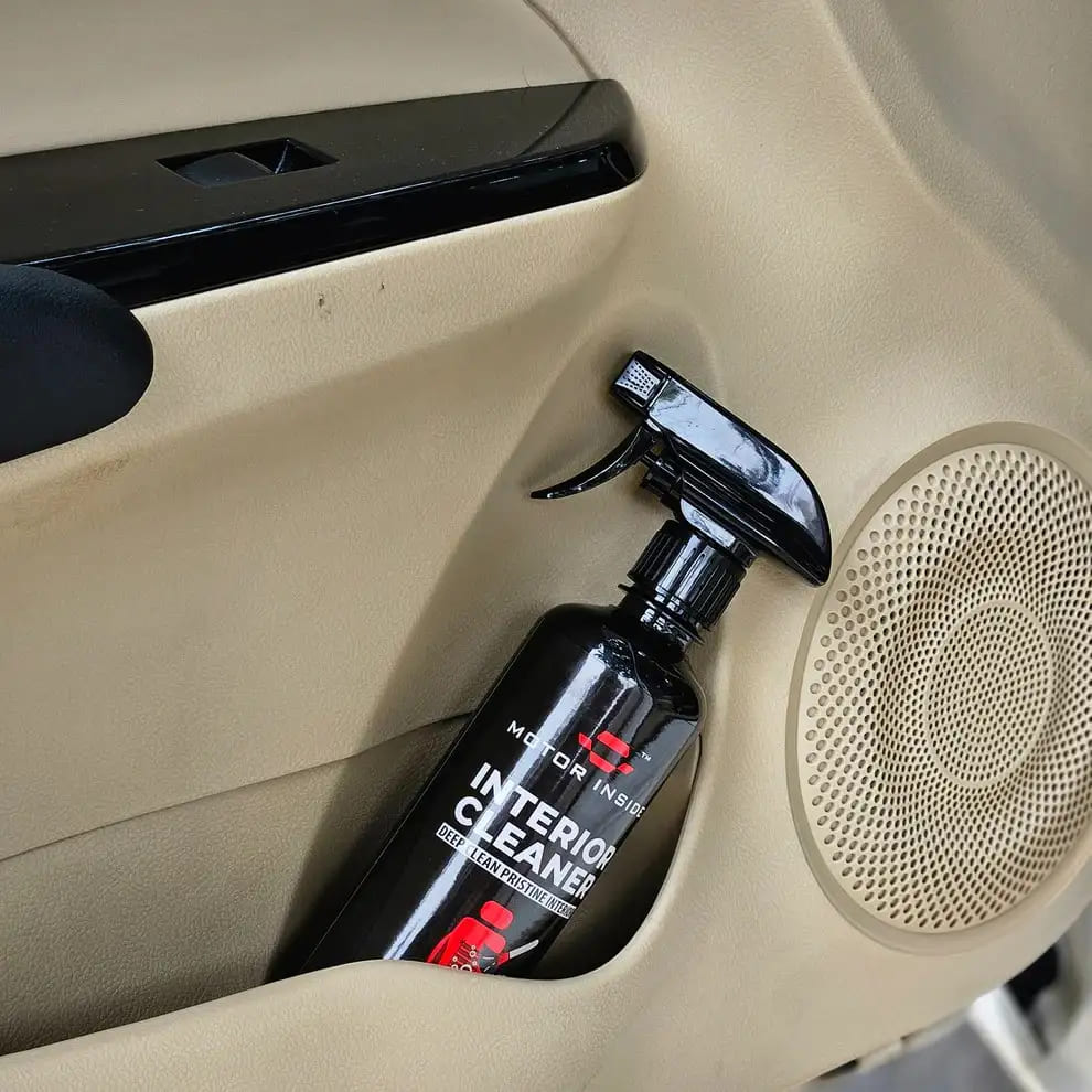 Spray bottle labeled 'Interior Cleaner' on a car's beige interior.