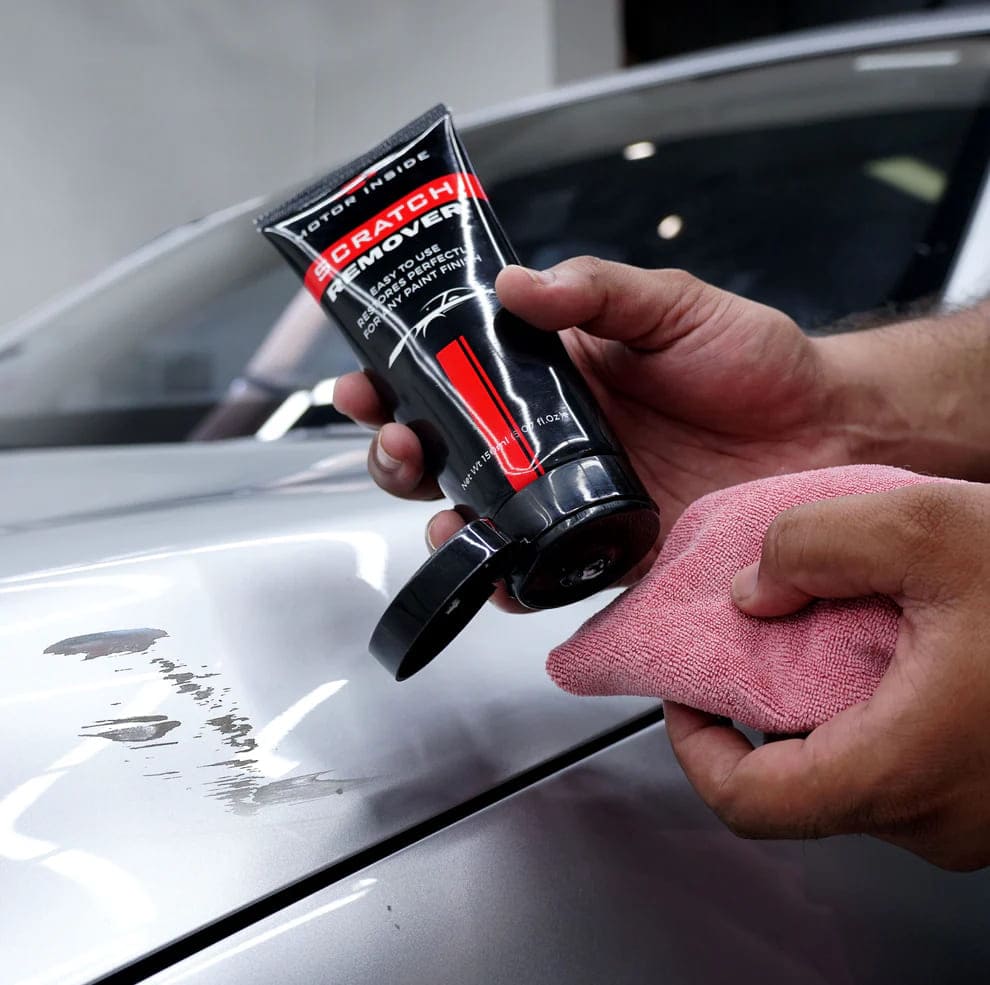 Person using a car scratch remover on a grey car