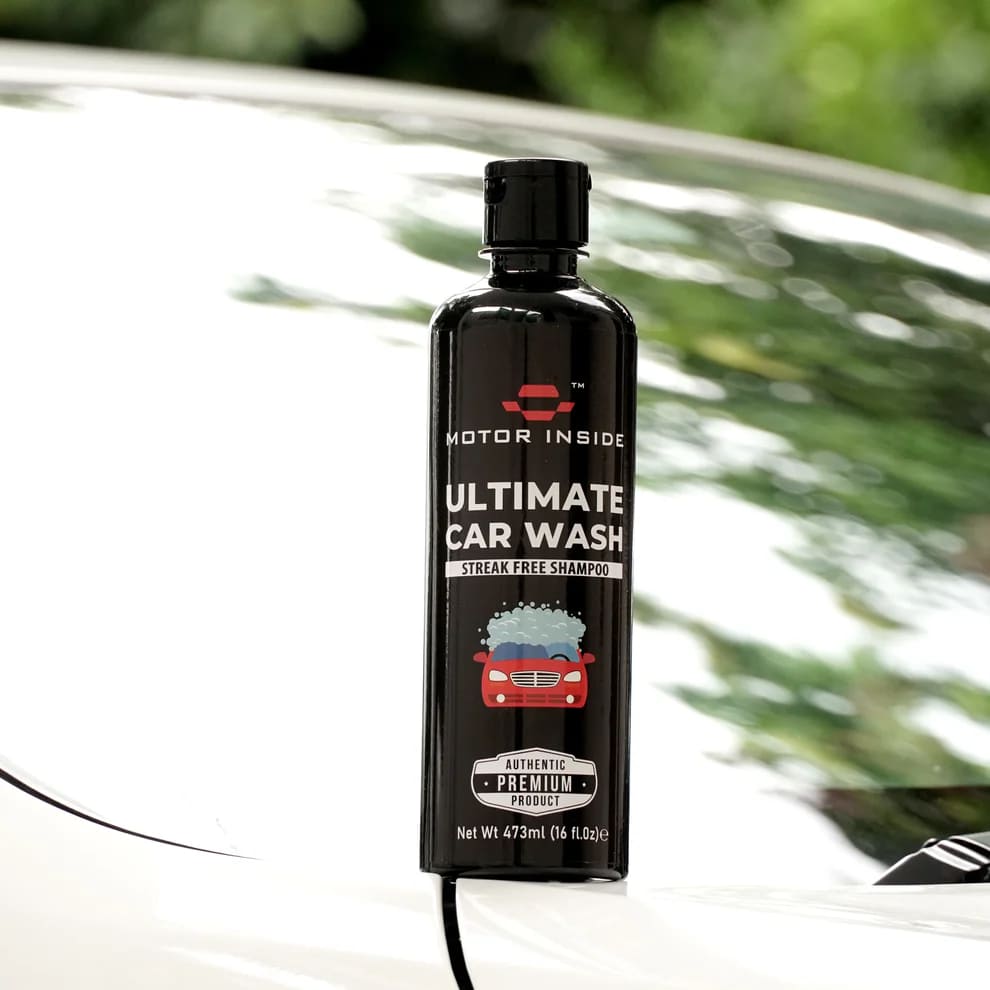 Bottle of 'Ultimate Car Wash' on a car bonet with blurred greenery in the background