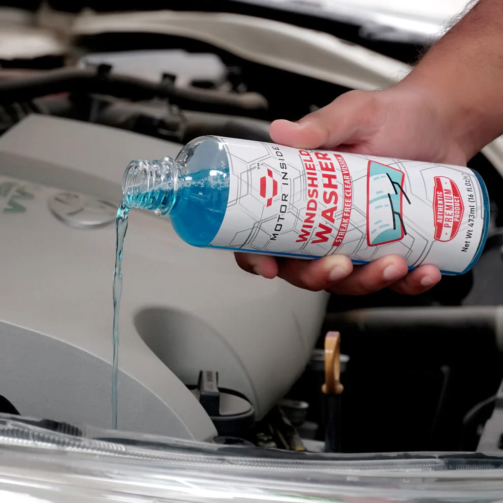 Person pouring windshield washer fluid from the bottle into car’s washer fluid reservoir